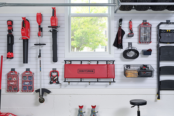 An organized garage wall, complete with slatwall and hooks, holding sets of red tools. 